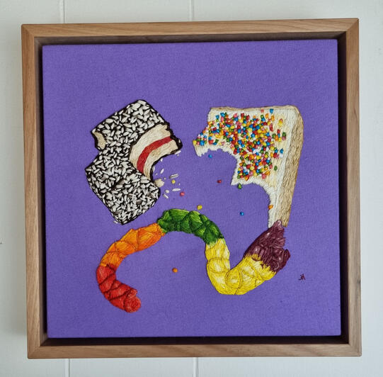 Hand embroidered fairy bread, lamington and Killer Python, all with bights taken out of them, on bright purple fabric
